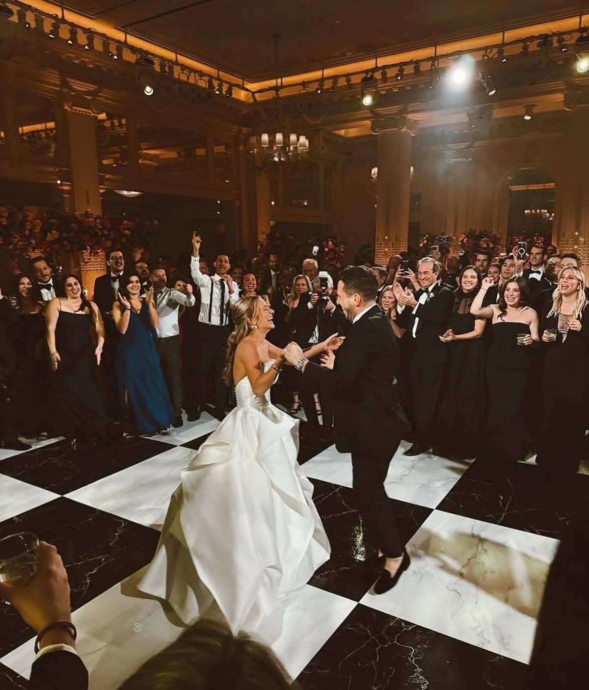 Couple sharing their first dance under string lights on a white dance floor at a San Francisco wedding reception